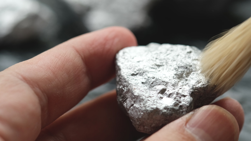 The man's hands were carefully sweeping dust or dirt from the platinum ore.