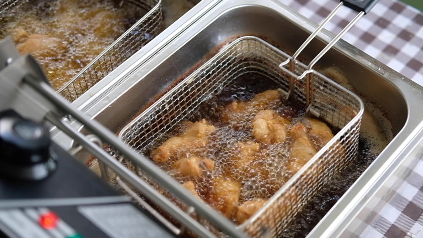 Frying chicken in deep fryer with bubbles of the oil are boiling while frying. Royalty-Free Stock Footage #1096467965