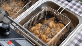 Frying chicken in deep fryer with bubbles of the oil are boiling while frying.