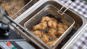 Frying chicken in deep fryer with bubbles of the oil are boiling while frying.