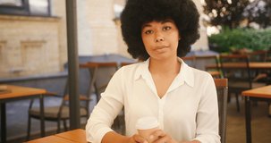 Latin woman has online meeting and talks about important details and plans for business project. Kinky-haired entrepreneur examines papers and tells about ideas