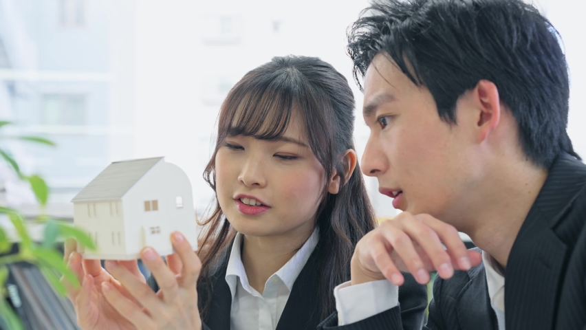 Group of young Asian businesspeople meeting with house model.