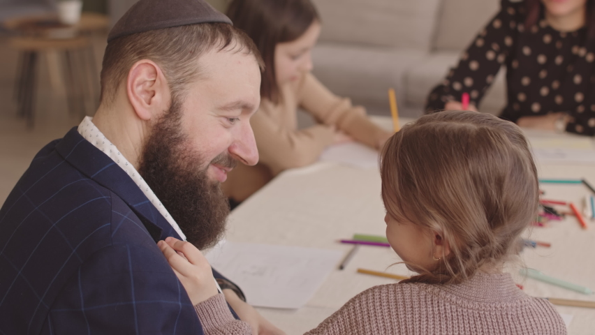 Jewish father and his little daughter looking at each other with candid smile while drawing postcards on Hanukkah with family at home Royalty-Free Stock Footage #1096471585