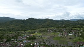 Amazing view from the residential area nestled under the mountains in Indonesia. Aerial drone footage.