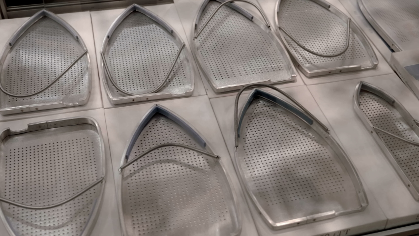 Rows of protective metal bases for irons of various shapes and purposes. Shot in motion. Closeup