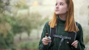 Hiker redhead woman eating a healthy no bake date bar, wearing a backpack. Trekking concept.