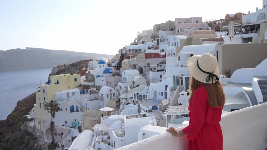 Attractive woman in Oia village looking cityscape from balcony in Santorini Island, Greece
