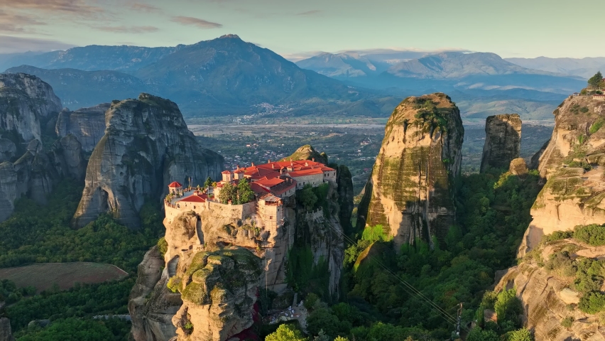 Flying over Meteora Monasteries at sunrise, Greece. Landscape scenery with green hills, rocks, and old Monasteries on it. Aerial view, 4K Royalty-Free Stock Footage #1096479715
