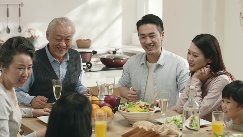 three generation asian family sitting at dining table having a pleasant conversation while eating meal Royalty-Free Stock Footage #1096488265