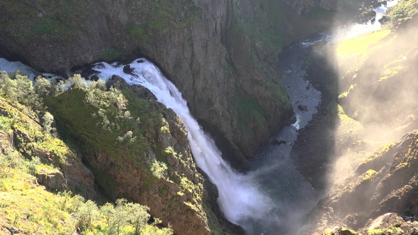 Picturesque waterfall in Norway. One of many beautiful waterfalls in the Geiranger fjord region, Norway. The powerful torrent of raging water falling from the forest-covered cliffs.