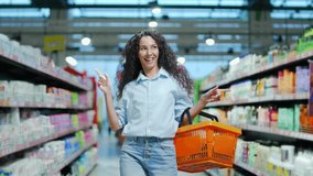 cheerful young woman customer in the store dances funny between the rows in a supermarket with a basket in his hands. walking the grocery store and moving like dancing while doing shopping having fun - Powered by Shutterstock - Get 15% off with code: PIKWIZARD15