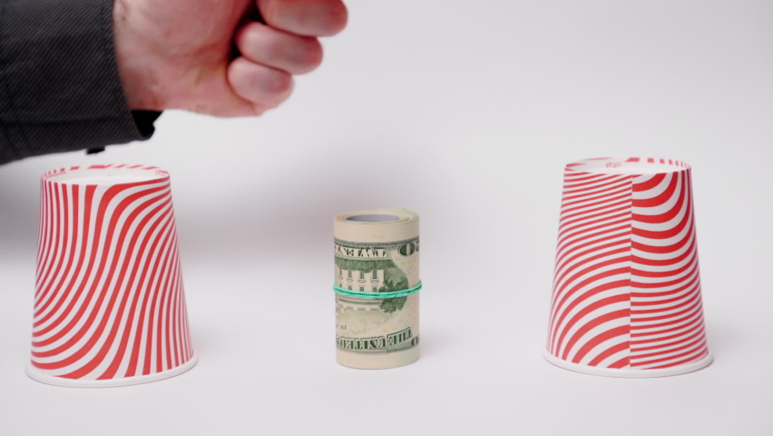 Money fraud. Close up of male hand choose paper cup with prize of rolled up dollar bills. White background. Concept of scamming, gambling and games. Royalty-Free Stock Footage #1096515311