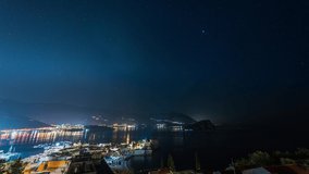 Amazing hyper lapse video of a clear night sky over illuminated Budva Old town and marina with boats, Montenegro. 