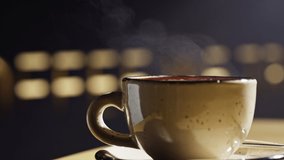 Close-up slow motion of a steaming cup of coffee. A cappuccino is standing on a table in a cafe and steam is coming out of it. High quality 4k footage