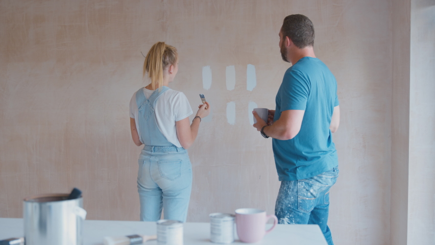Couple renovating kitchen at home painting tester paint colour strips on plaster wall - shot in slow motion Royalty-Free Stock Footage #1096518537
