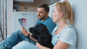 Couple on coffee break from renovating kitchen at home playing with pet Spaniel dog looking at paint colour swatches - shot in slow motion - Powered by Shutterstock - Get 15% off with code: PIKWIZARD15