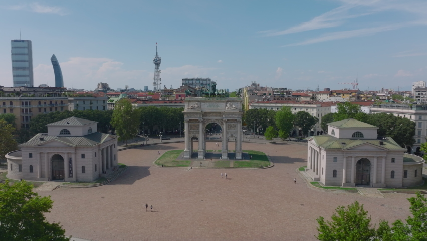 Fly over old triumphal arc with equestrian statues on top. Famous historic landmark on round square. Milano, Italy