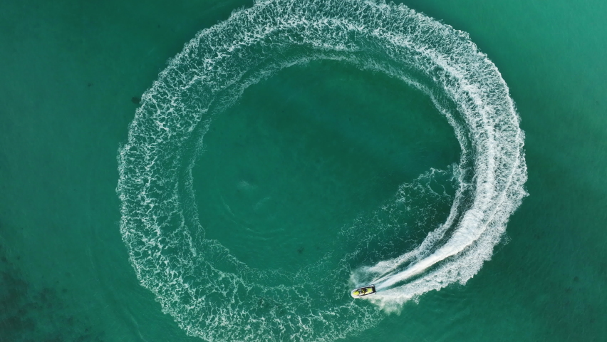 Tourist playing a personal watercraft above fast water scooter in the sea, going around in circle making beautiful white foamy waves in clear Pacific Ocean. clear turquoise at tropical beach.  Royalty-Free Stock Footage #1096522791