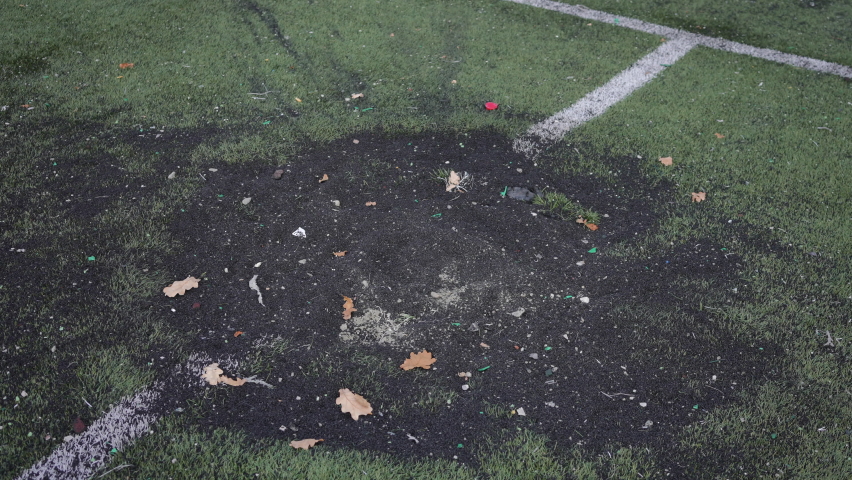 Black burnt bomb hole on sports field outdoors in Kiev Ukraine suburb. Missile spot after air raid attack on stadium. Destruction and war concept