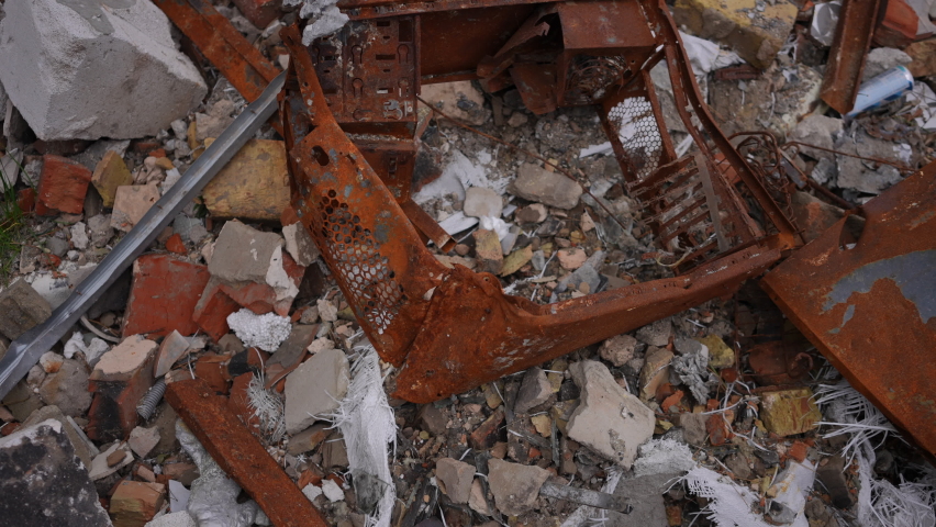 Mangled metal bricks and ashes outdoors in bombed demolished city in Ukraine. Close-up war garbage in town after bombardment attack. Russian military invasion concept