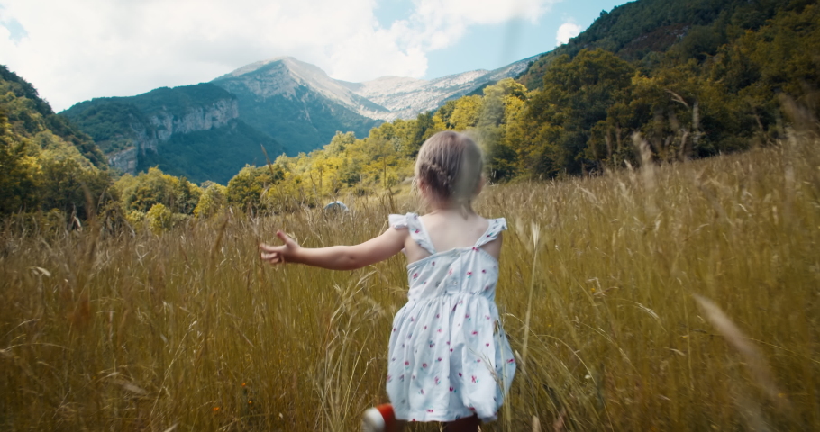 Happy cute toddler girl run on mountain meadow at summertime vacation. Children leads active lifestyle outdoors on weekend. 