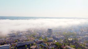 The center of a small green town where the morning fog forms a wonderful effect together with the sunlight. Drone video. 4K.