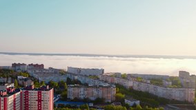 Wide view of a European city in perfect morning, with fog, lots of light and green trees. Drone video.