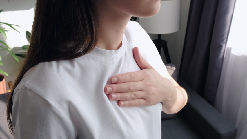 Close up side view of ill young woman putting hand on chest, feels discomfort. Having pain in chest, Gastroesophageal Reflux Disease have frequent belching. Healthcare medical and people concept | Shutterstock HD Video #1096538447