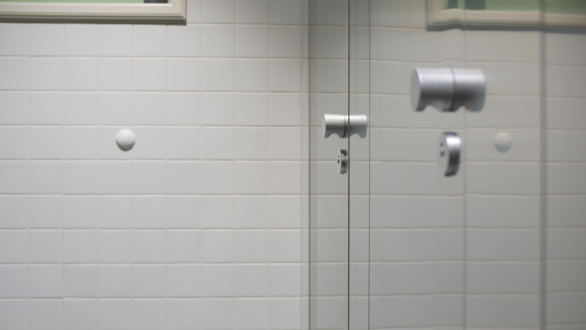 Cropped shot of man in suit with upset stomach walk into toilet cabin. Businessman having diarrhea using stall in public restroom. Realtime. 