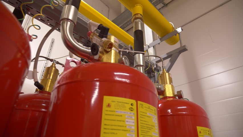 Professional modern industrial fire extinguishing system. Rows of red metal cylinders of fire extinguishers in a special fire safety room. Fire prevention. Means for extinguishing fires. Royalty-Free Stock Footage #1096539335