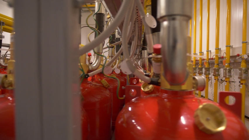 Modern industrial professional  fire extinguishing system. Rows of red metal cylinders of fire extinguishers in a special fire safety room. Fire prevention. Means for extinguishing fires. Royalty-Free Stock Footage #1096539351