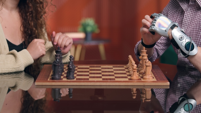 Cropped shot of man with bionic arm playing chess with girlfriend. Close up of disabled man with hand prosthesis move chess figure playing with friend Royalty-Free Stock Footage #1096543685
