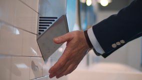 Cropped shot of man in suit using hand dryer in public bathroom. Realtime.  - Powered by Shutterstock - Get 15% off with code: PIKWIZARD15