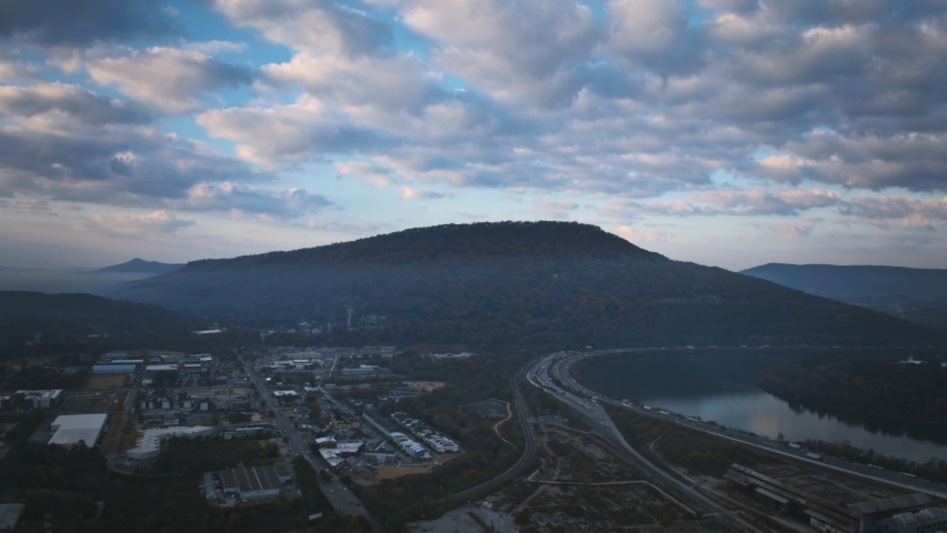 Aerial hyperlapse timelapse focused on Lookout Mountain during the sunrise with clouds in the sky, boats in the Tennessee River and traffic on the highway.