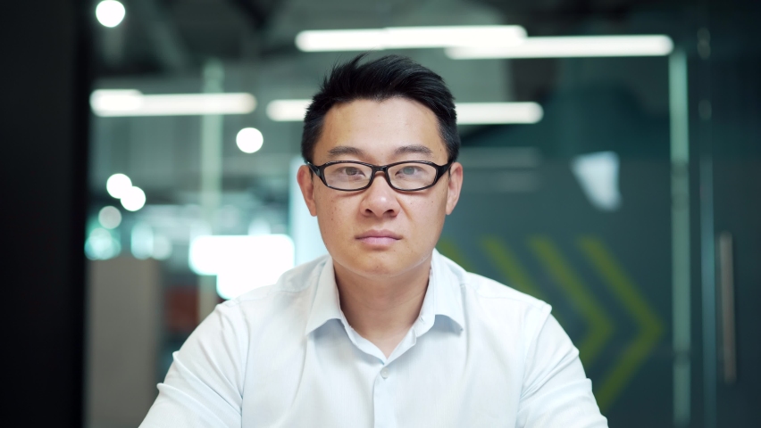 surprised asian man shoots glasses shocked looking at camera. Happy smiling rejoices. Look at monitor screen webcam view. amazed close up portrait. Face Handsome man Office worker wow expression Royalty-Free Stock Footage #1096552207