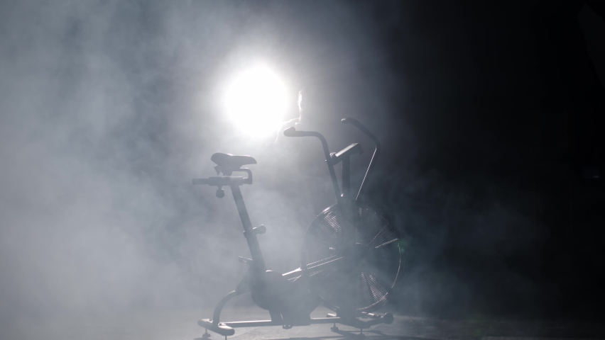 Active man spinning an air bike in the gym. Air bike training in slow motion. Aggressively Muscular Pedaling on a Stationary Be in a Dark Gym
 Royalty-Free Stock Footage #1096555163