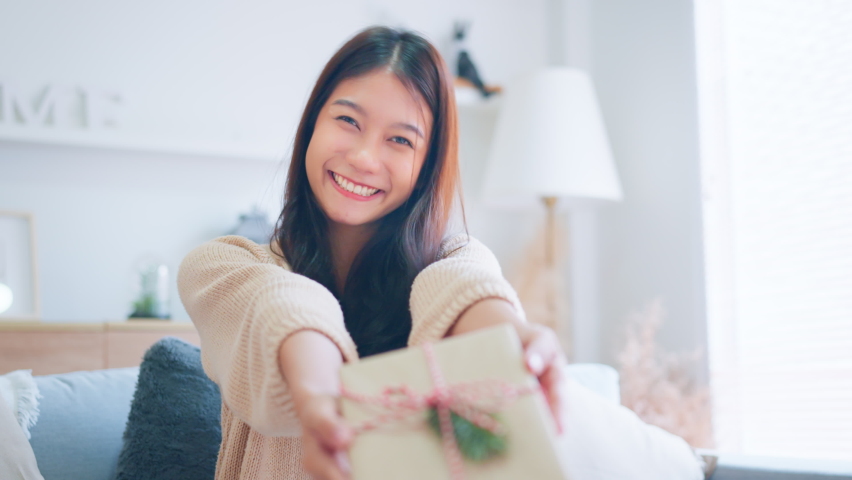 Giving a gift, Happy young asian woman giving handmade present wrapped paper. Christmas time. New Year's Eve and gift giving