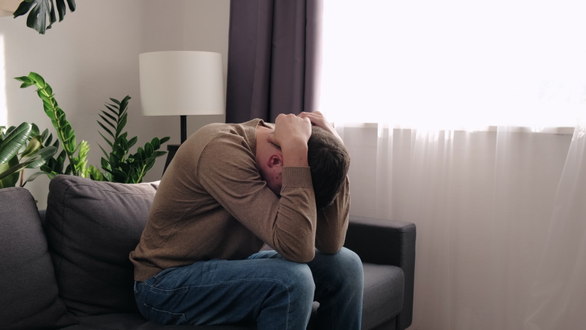 Depressed sad young man 30s in trouble sitting on couch holding head in hands feeling pain lonely heartbroken upset worried hopeless. Stressed guy loser having problems. Regrets and mistake concept | Shutterstock HD Video #1096556331