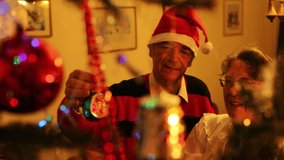 Senior Man Decorating Christmas Tree with Vintage Decorations At Home With his Beloved Wife 