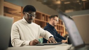 Portrait of Enthusiastic Black Man Turning on his Laptop and Starting his Work Day at the Office. Male Graphic Designer Smiling While Developing a New Visual Concept. Handheld Shot - Powered by Shutterstock - Get 15% off with code: PIKWIZARD15