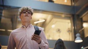 Portrait of University Student Checking his Text on his Smartphone and Smiling While he Walks Toward Classroom. Young White Man Male Crossing the Hall of a Big Building. Low Angle, Slow Motion Shot - Powered by Shutterstock - Get 15% off with code: PIKWIZARD15