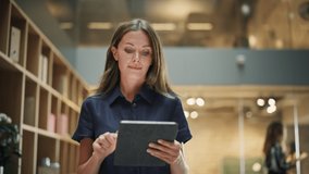 Close Up of a Content Female CEO Making Notes on her Tablet. Portrait of a Caucasian Woman Crossing a Corporate Office Hall, Smiling and Looking Confident. Low Angle, Slow Motion - Powered by Shutterstock - Get 15% off with code: PIKWIZARD15