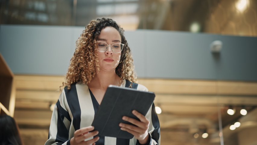 Portrait of a Powerful Female Leader Checking Meeting Briefing on her Tablet and Walking in Busy Corporate Office. Confident Hispanic Team Leader Preparing for a Presentation. Low Angle Slow Motion Royalty-Free Stock Footage #1096559181