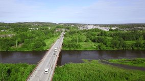 Aerial top down view of small road bridge across the river in rural area. Clip. Cars driving on the bridge and green vegetation.