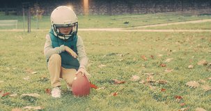 Family fun outdoors, Cheerful happy child in helmet playing American football outdoors in sunny day at public park. Family sports weekend. 4K video.