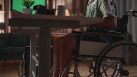 Side View Of Asian Man In Wheelchair Drinking Coffee While Using Mock Up Green Screen Desktop Next To The Camera At Home
