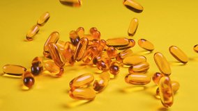 Omega fish oil dietary supplement falling on yellow background. Omega fish oil softgels dietary supplement background. Healthy life and heart health concept. Slow motion - Powered by Shutterstock - Get 15% off with code: PIKWIZARD15