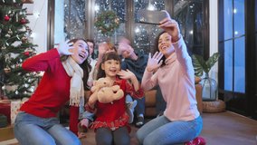Multi-ethnic big family use mobile phone video call online to relative. Attractive senior couple, parents with young kid daughter talking on smartphone during holiday Christmas, Thanksgiving seasonal.
