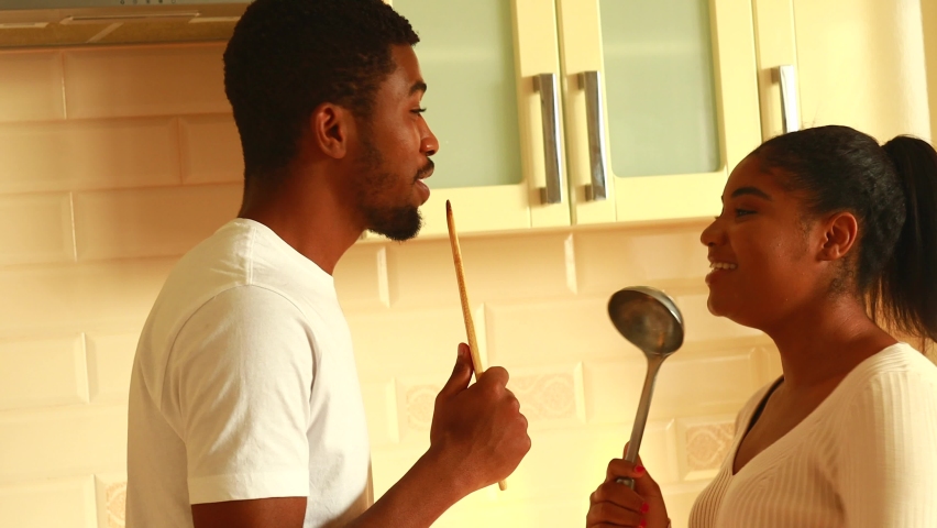 hispanic couple singing together holding a ladle like a microphone in the kitchen Royalty-Free Stock Footage #1096576299