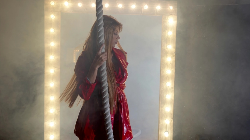 excited beautiful woman in red leather suit is moving and dancing seductively in smoke